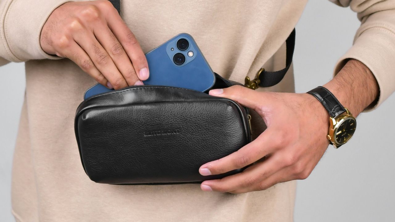 A man putting his phone into a crossbody bag